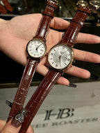 Pair of luxury wrist watches with brown leather straps and white dials