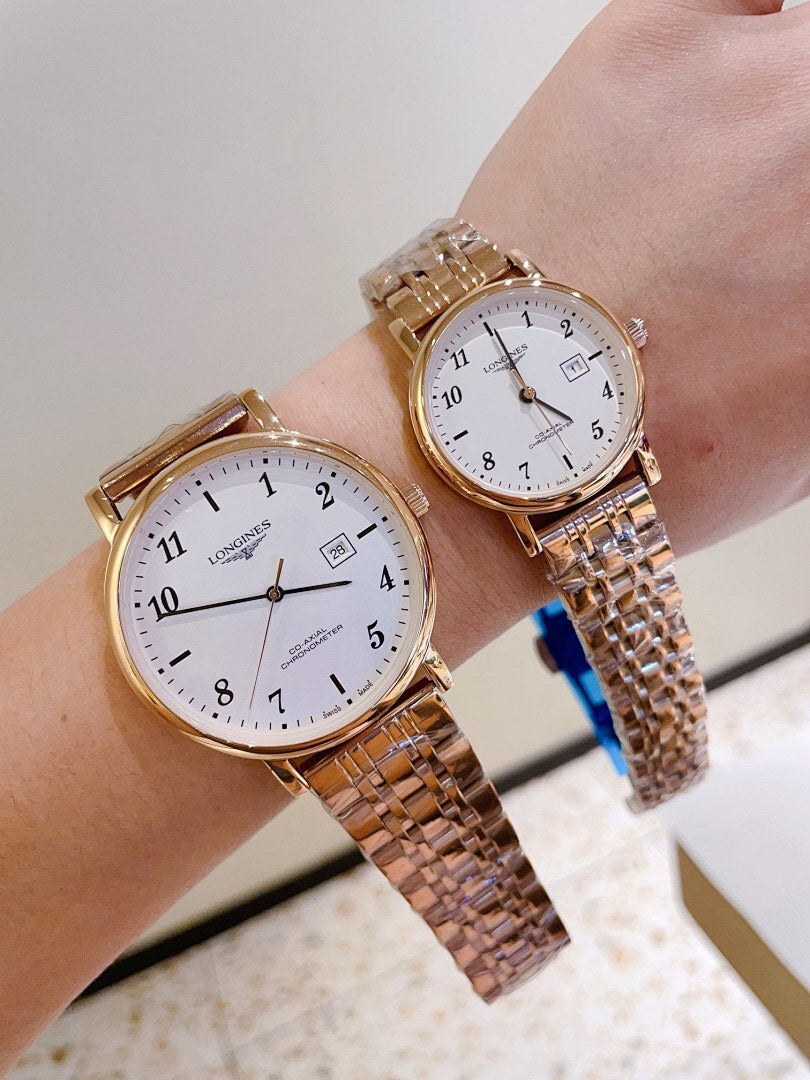 Two silver-tone wrist watches with white dials and metal link bracelets on hands