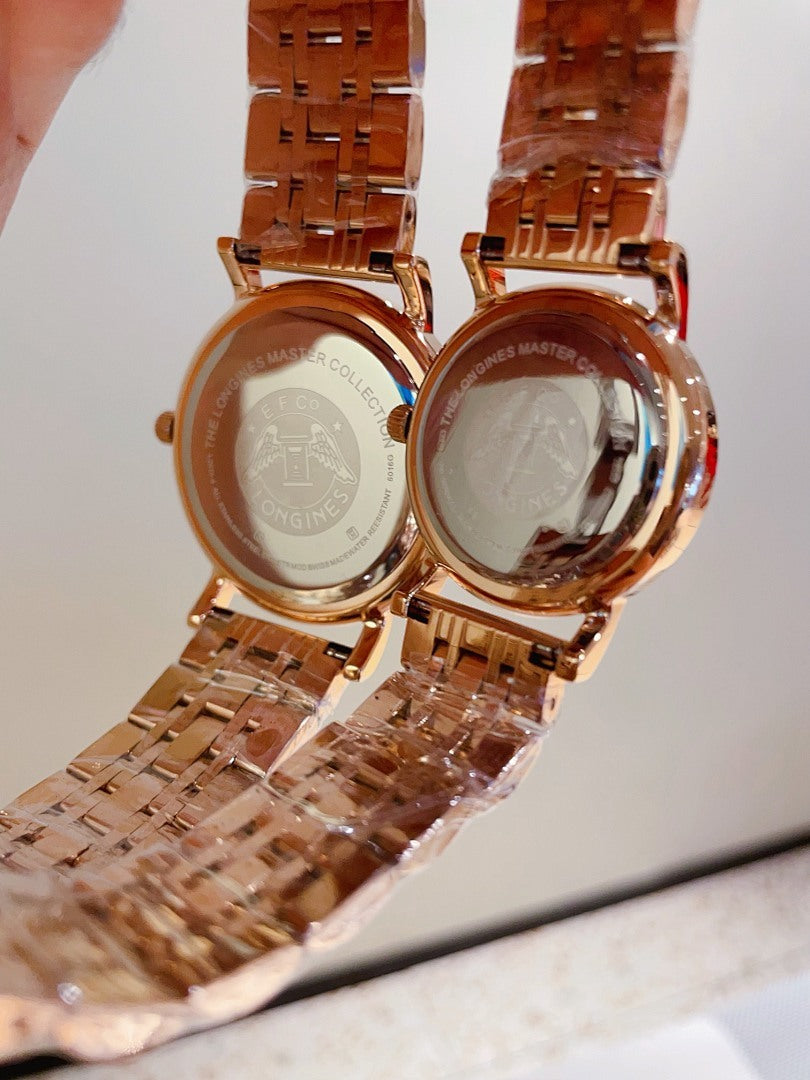 Two rose-gold-tone wrist watches with clasp backs facing the camera, metal bracelets