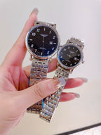 Two silver-tone wrist watches with dark dials and metal link bracelets held up