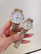 Two wrist watches with white dials and metal link bracelets held in hands
