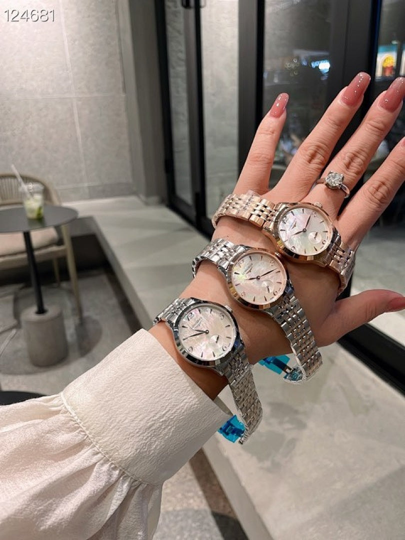 Longines watches with silver metal bracelets on hand, light dial faces.
