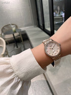 Longines watch on wrist with silver metal bracelet and light dial face.
