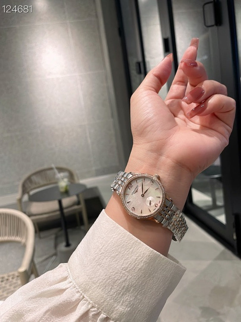 Longines watch on wrist with silver metal bracelet and light dial face.
