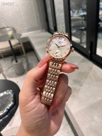 Longines watch held in hand with rose-tinted dial and silver metal bracelet.