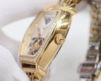 Gold-tone rectangular watch case with diamond bezel edge and crown on side.