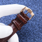 Longines wristwatch with brown leather strap and gold-tone buckle, close-up