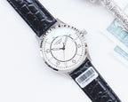 Silver analog watch with black leather strap and white dial, gold-toned crown.