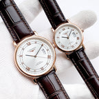 Longines watch with brown leather strap, white dial, Roman numerals and date at 3 o'clock.