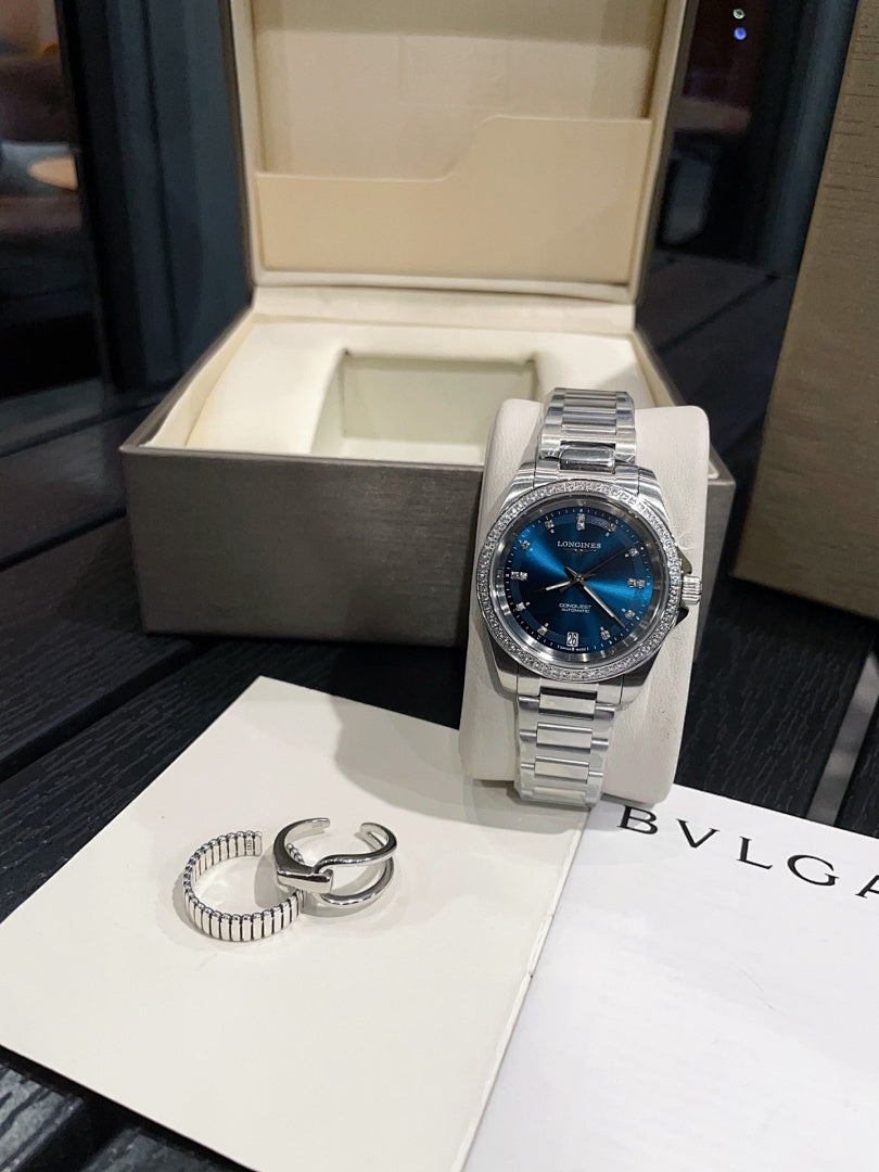 Stainless steel wristwatch with blue dial and metal bracelet on display stand