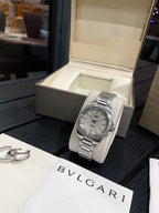 Stainless steel wristwatch with silver dial and metal bracelet on white cushion