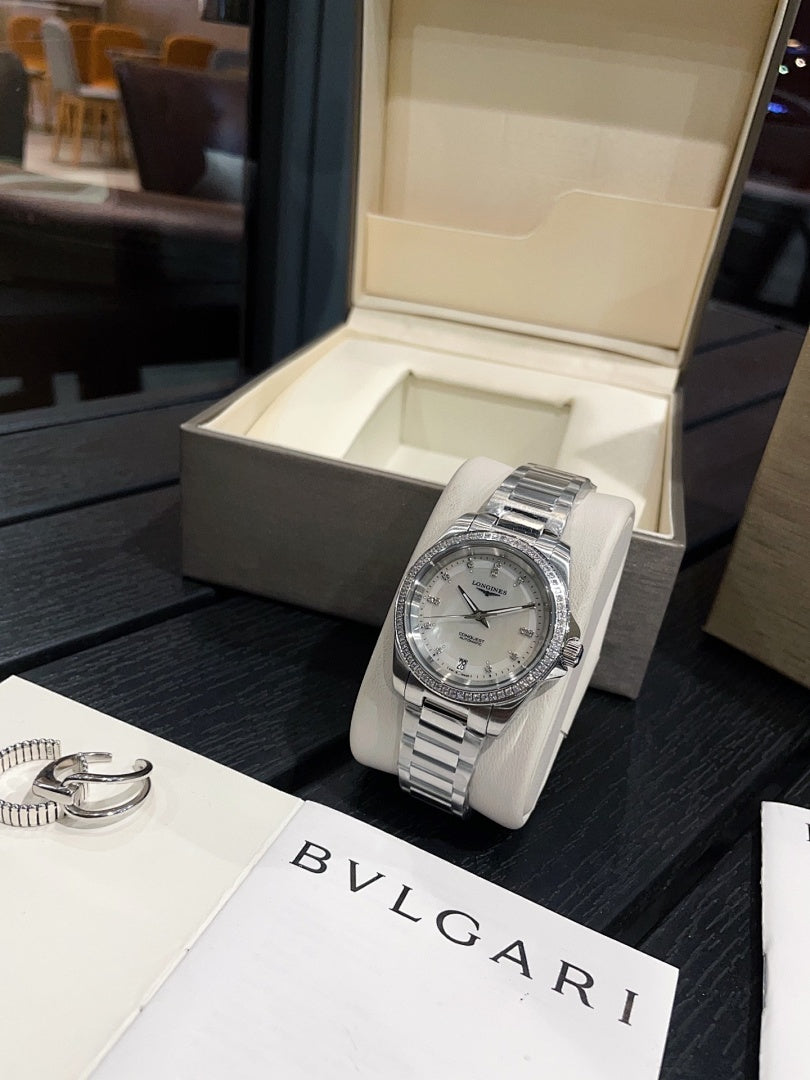 Stainless steel wristwatch with silver dial and metal bracelet on white cushion