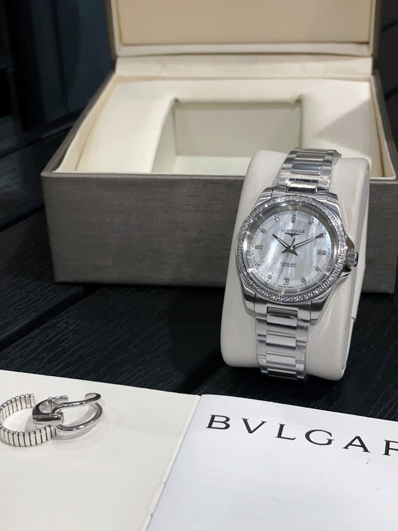 Stainless steel wristwatch with white dial and metal bracelet on display stand