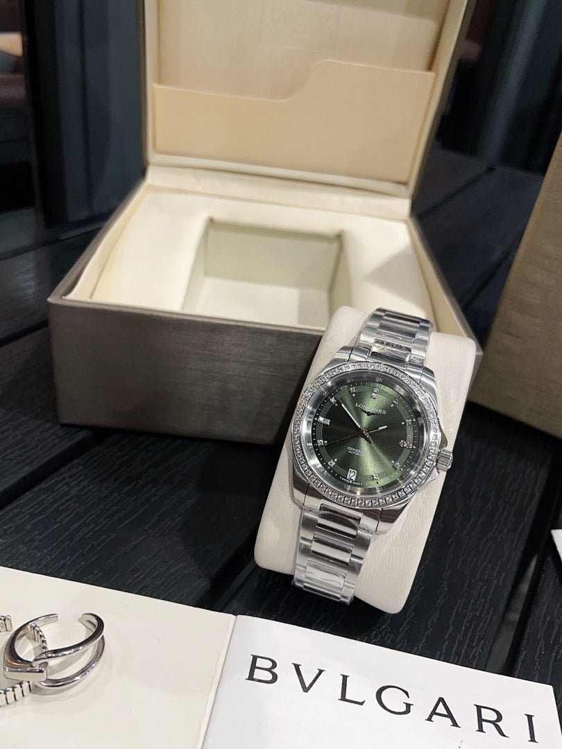 Stainless steel wristwatch with green dial and metal bracelet on white stand