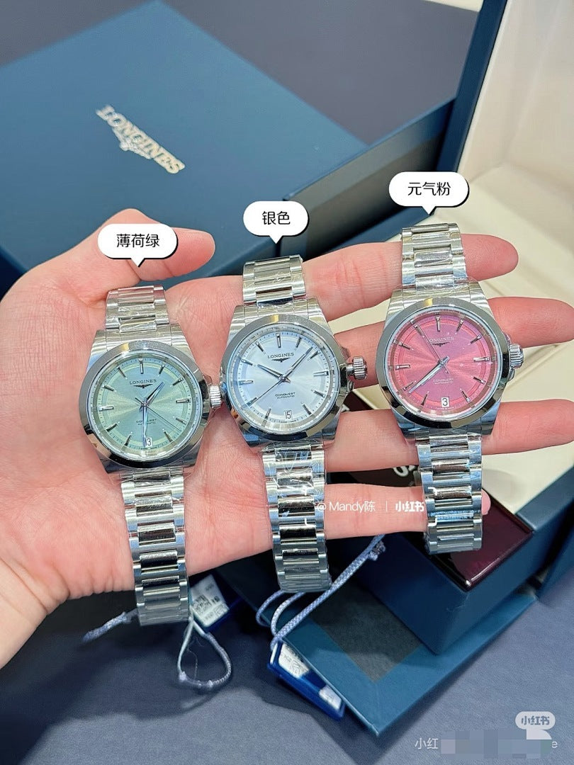 Longines wristwatch trio with silver metal bracelets and light blue, white, and pink dials.