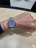 Longines wristwatch with silver metal bracelet and blue dial on wrist.
