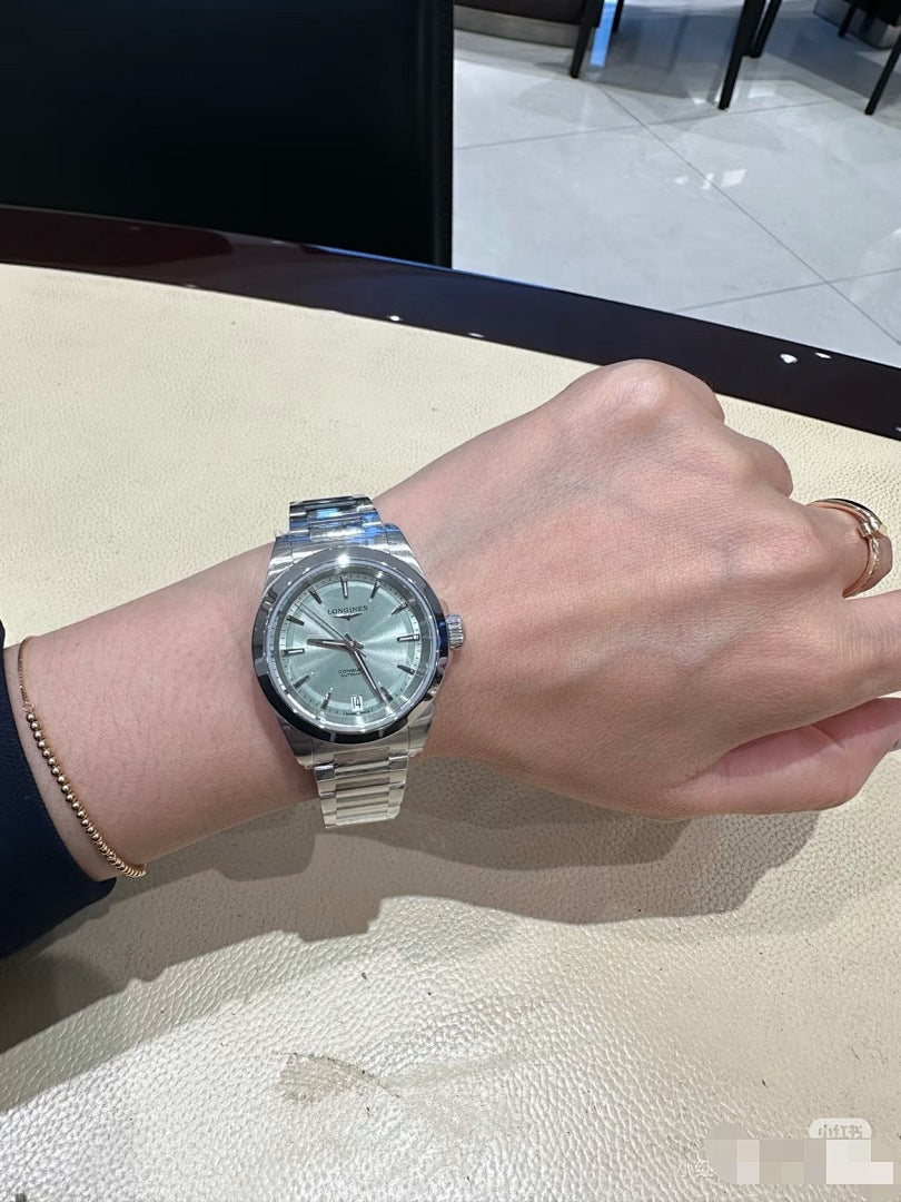 Longines wristwatch with silver metal bracelet and light blue dial on wrist.