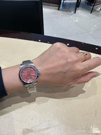 Longines wristwatch with silver metal bracelet and pink dial on wrist.