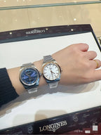 Longines wristwatch pair with silver metal bracelets and blue and white dials on case.