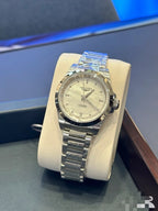 Longines wristwatch with silver metal bracelet and light dial, angled view on stand.
