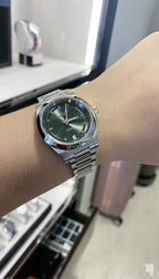Longines watch on wrist, green dial and silver stainless steel bracelet, round case