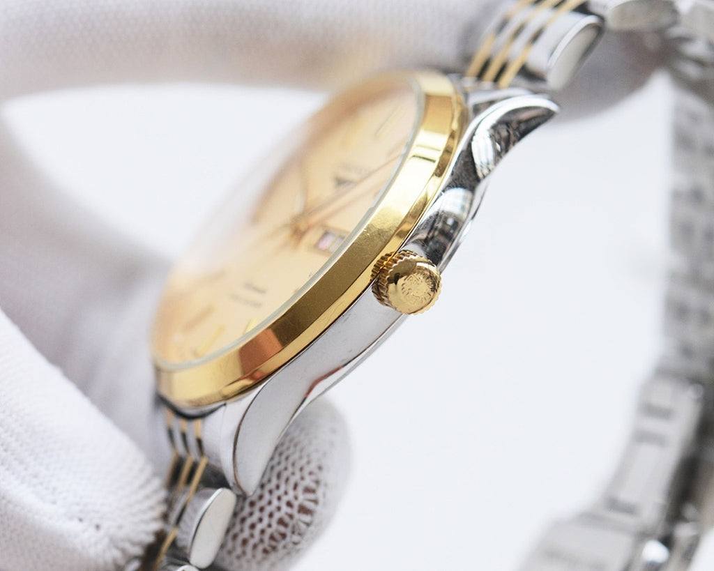 Two-tone Longines watch with gold-tone bezel and silver case, visible crown