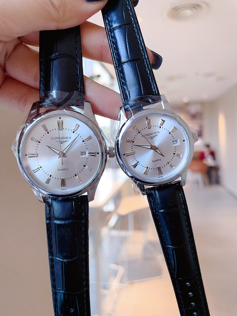 Longines watch pair with dark blue leather straps and white dials, held up.