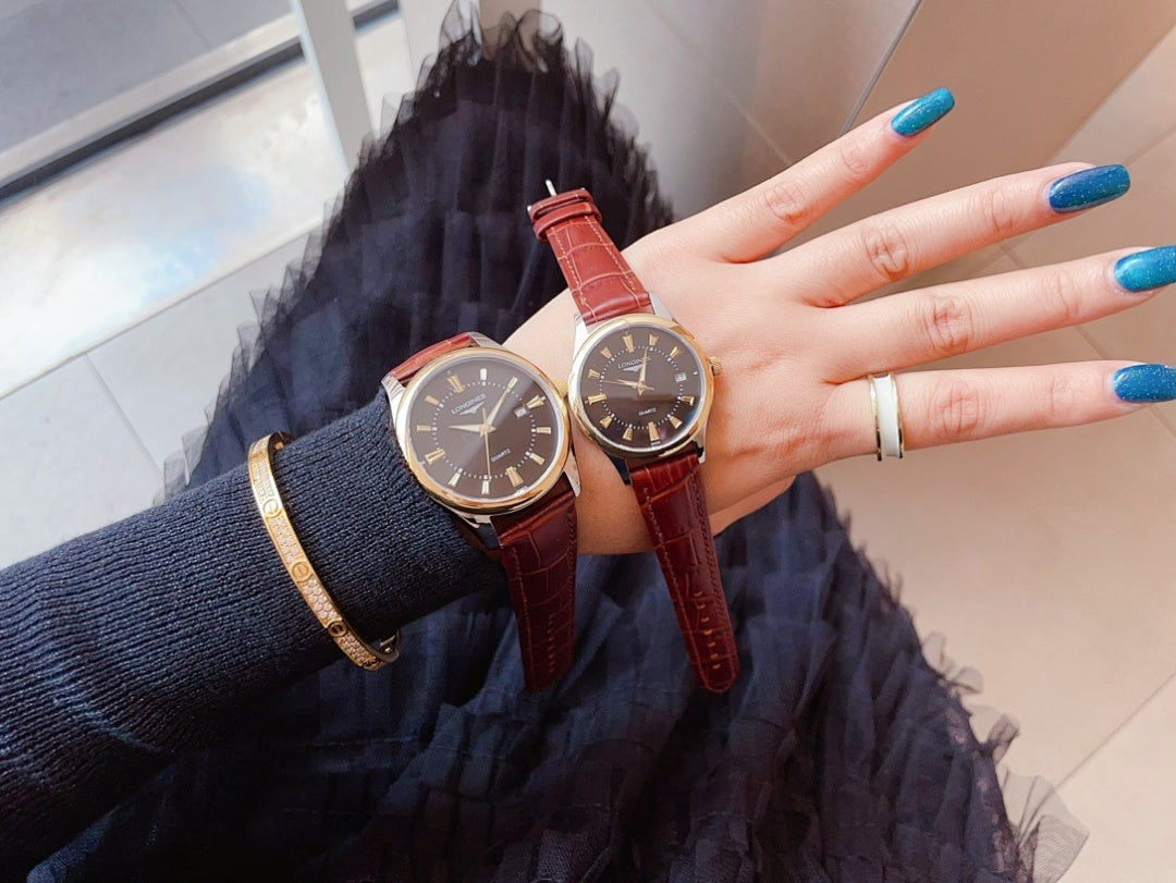 Longines watch pair with red leather straps and dark faces, held in hand.