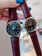 Longines watch pair with blue dials and burgundy leather straps, held in hand.