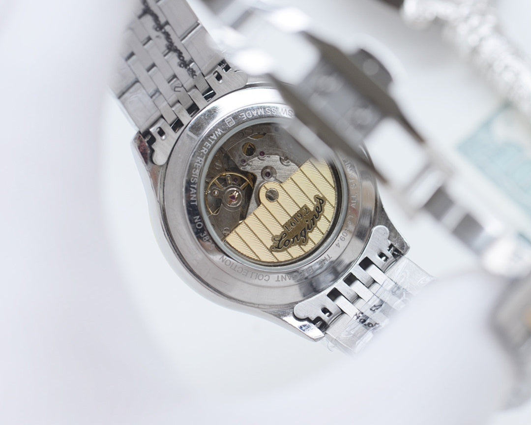 Longines wristwatch case back with visible movement inside a stainless bracelet.
