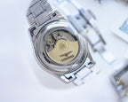 Longines wristwatch caseback view, exposed movement, silver link bracelet.