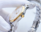 Longines wristwatch side view, gold-tone accents on silver case, crown visible.