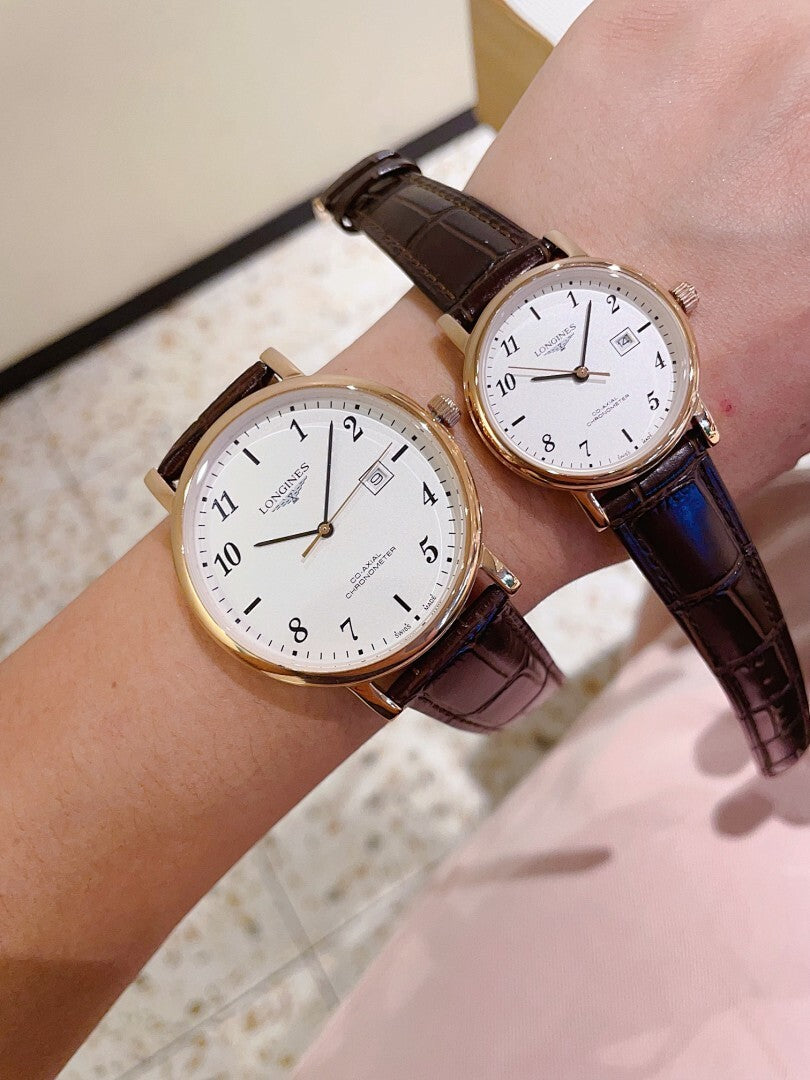 Pair of Longines watches with white dials and brown leather straps, gold-tone cases.