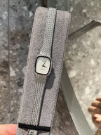 Square wristwatch with light dial and silver mesh strap, close-up on stand