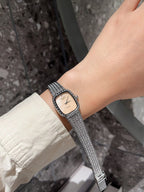 Square wristwatch with light dial and silver mesh bracelet on wrist