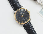 Longines wrist watch with gold-tone case, dark dial, black leather strap.