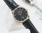 Longines wrist watch with gold-tone case, dark dial, black leather strap.