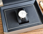 Automatic wristwatch by Longines, silver dial, black leather strap, displayed in a black box