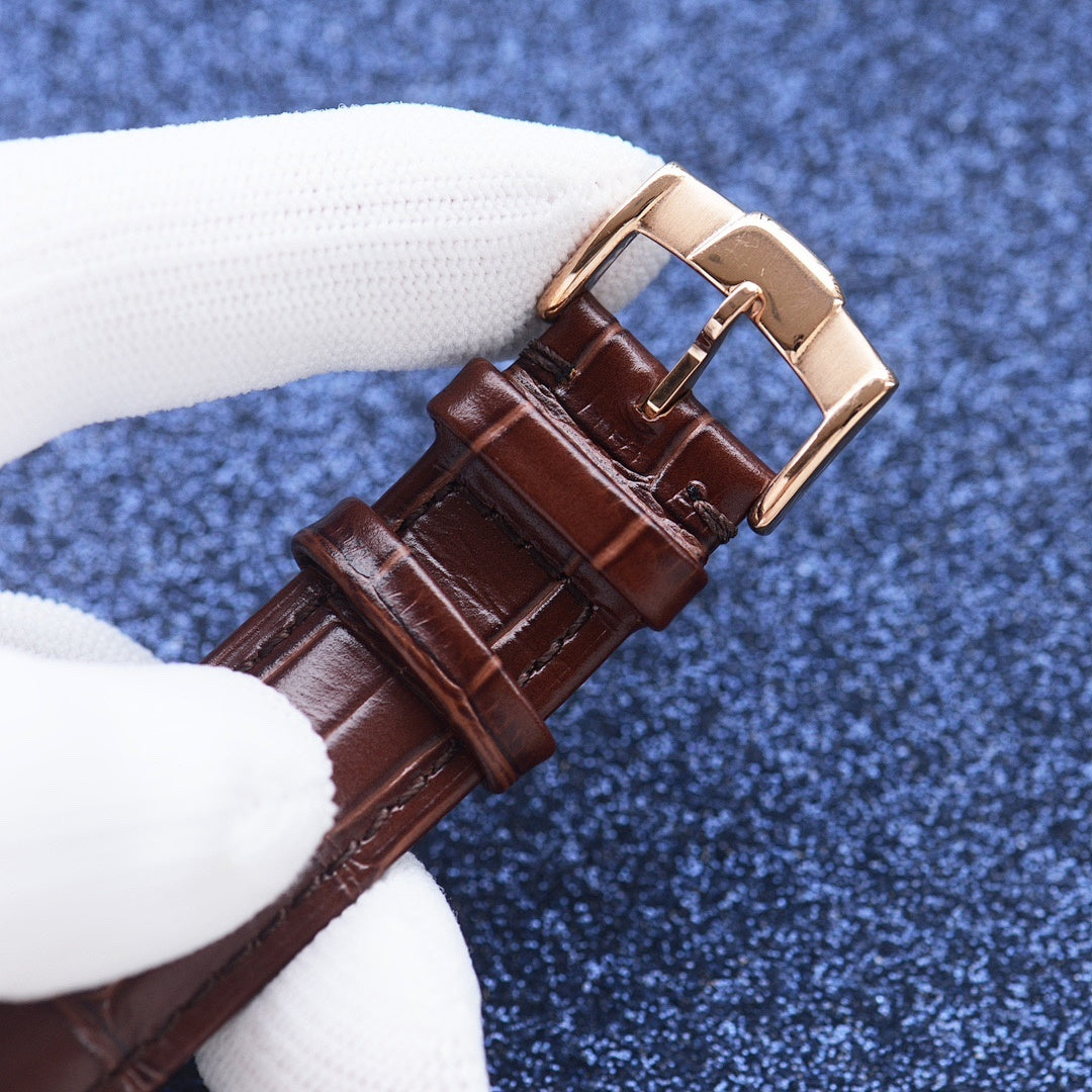 Brown leather-strap wristwatch with gold-tone buckle, close-up.