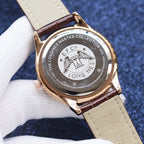 Gold-tone case wristwatch with brown leather strap and engraved case back.