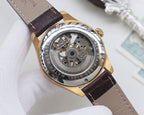 Skeleton analog watch with brown leather strap and gold case, visible mechanical movement