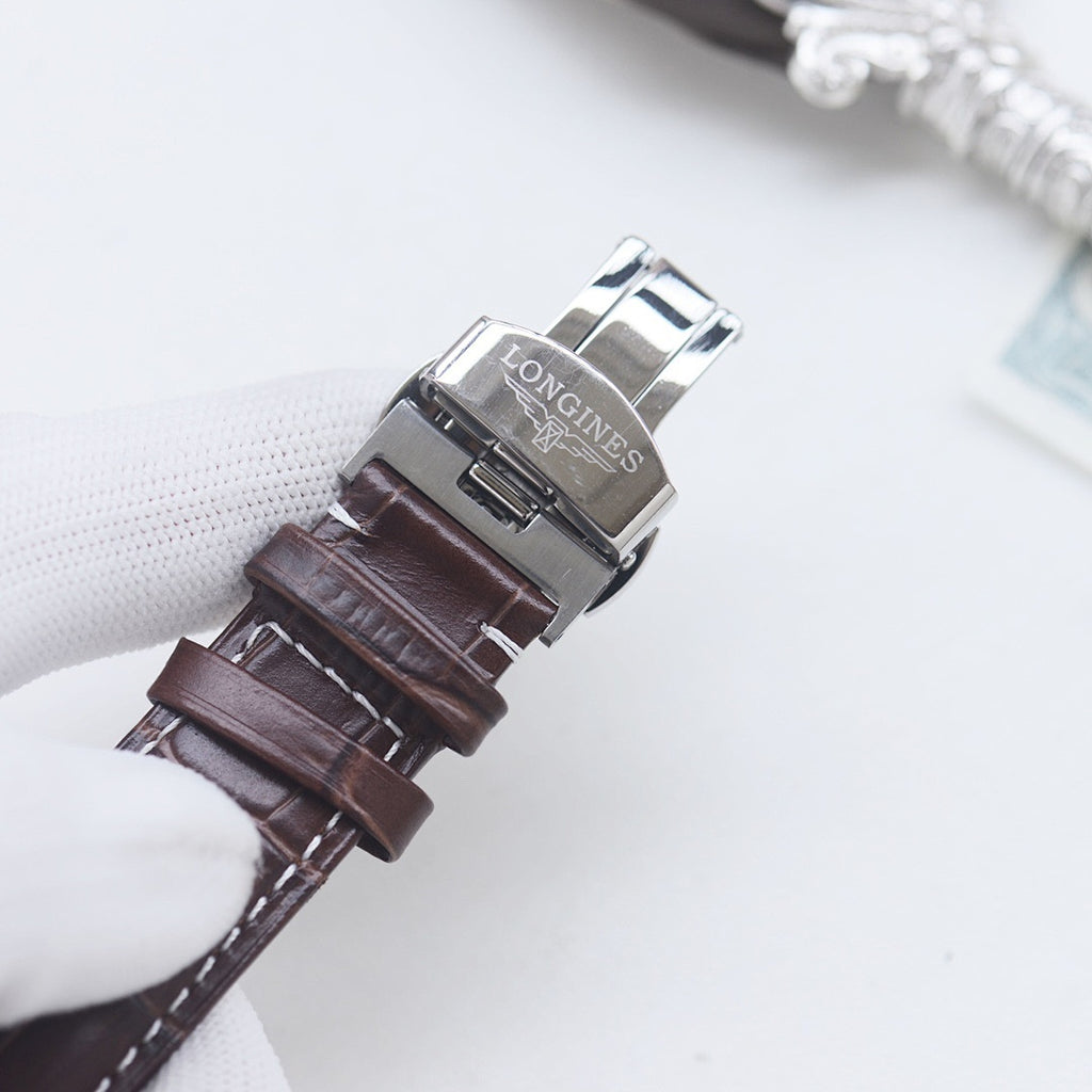 Longines wristwatch with brown leather strap and silver buckle, showing clasp underside.