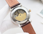 Round watch with open case showing gold-toned movement, brown leather strap