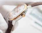 Gold-tone round watch with brown leather strap and crown detail