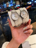 Longines stainless steel watch with silver bracelet and white dial, held in hand