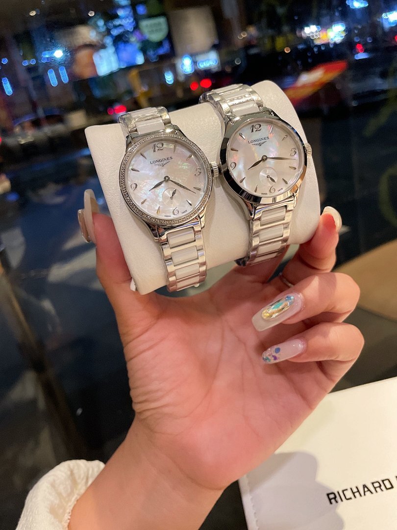 Longines stainless steel watch with silver bracelet and white dial, held in hand
