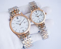 Two-tone wristwatch pair with white dials, Roman numerals, and metal link bracelets