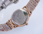 Two-tone wristwatch caseback on metal strap, rose-gold tone with engraved back