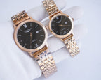 Two-tone wristwatch pair with black dials, Roman numerals, and metal link bracelets