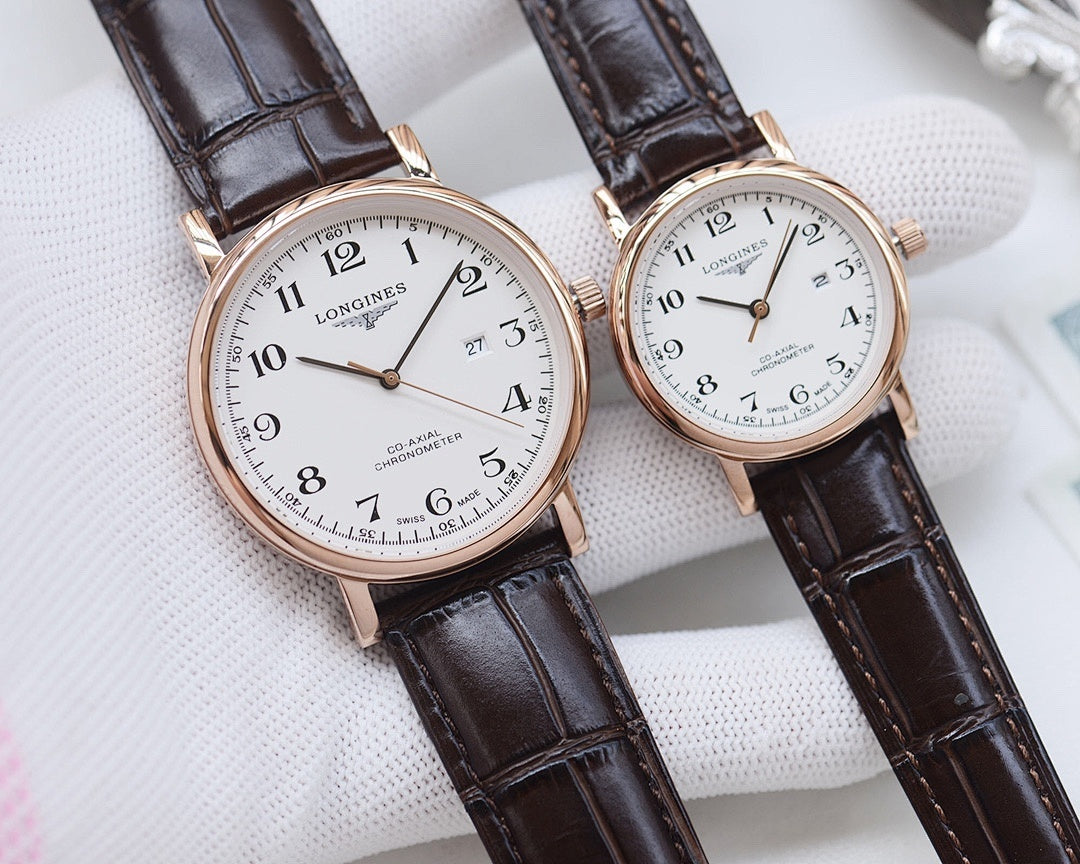 Longines watch pair with white dials, rose-gold cases, and dark brown leather straps on pillow